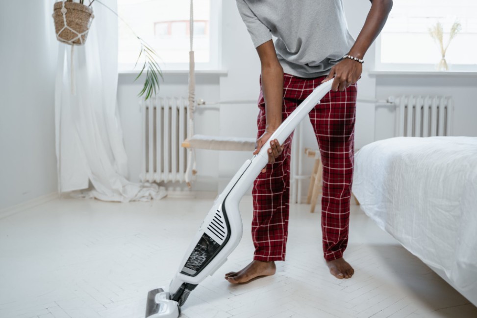 A man cleaning the floor using a vacuum