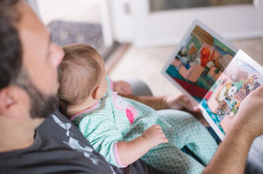 a father reading book to his baby 