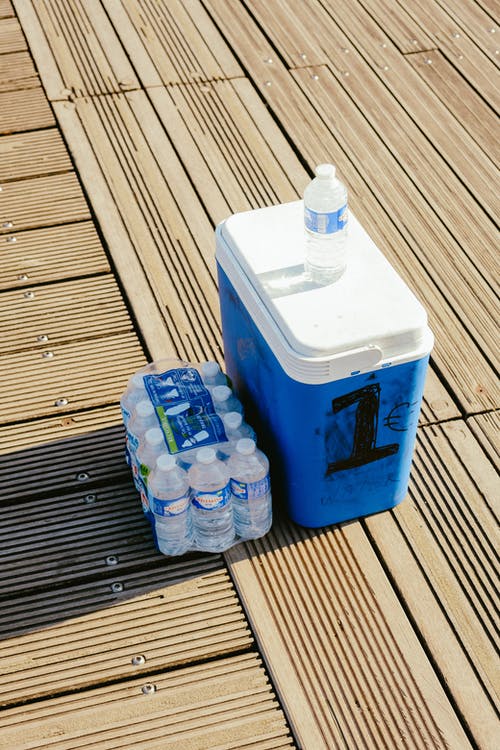A blue cooler with bottled waters on the side